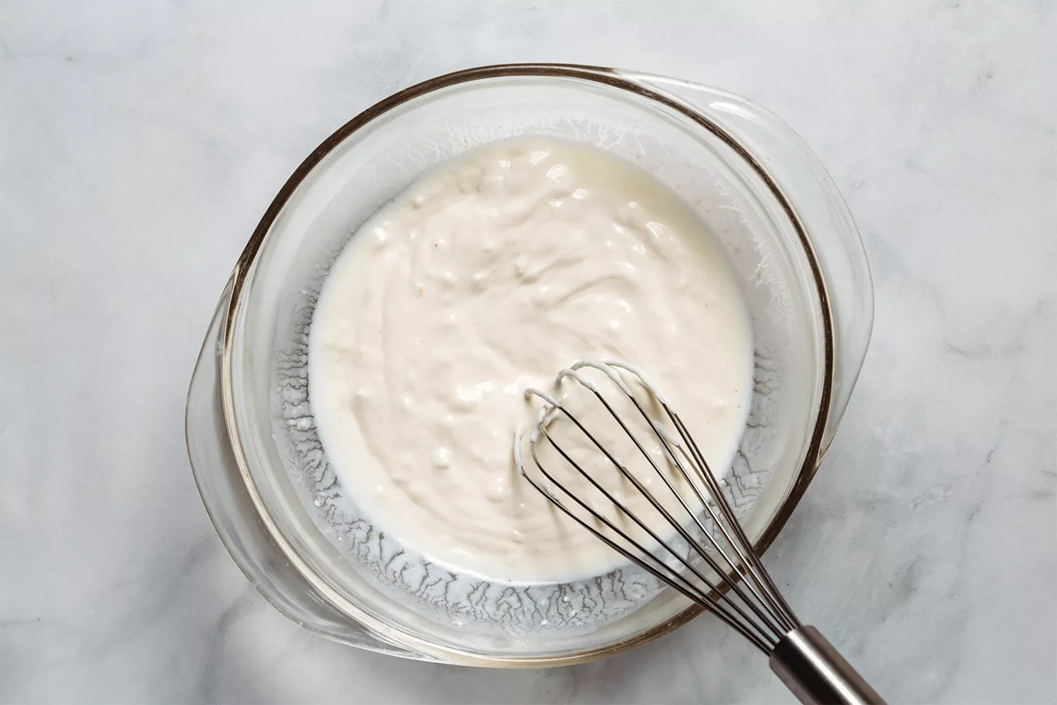 Buttermilk, maionese e creme de leite em uma tigela com um batedor