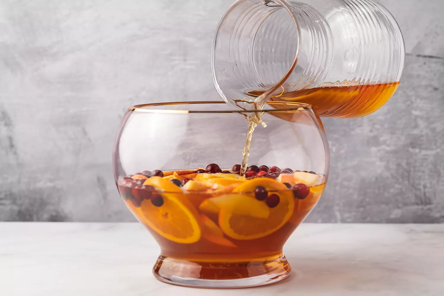 Suco, frutas e sucos de frutas adicionados a uma tigela de ponche para o coquetel de Ação de Graças